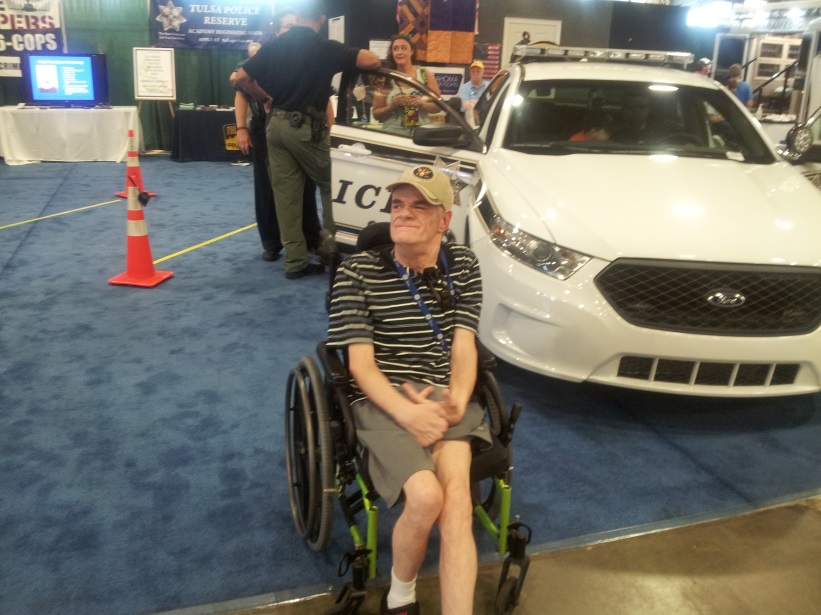Man in Wheelchair in Front of a Police Car
